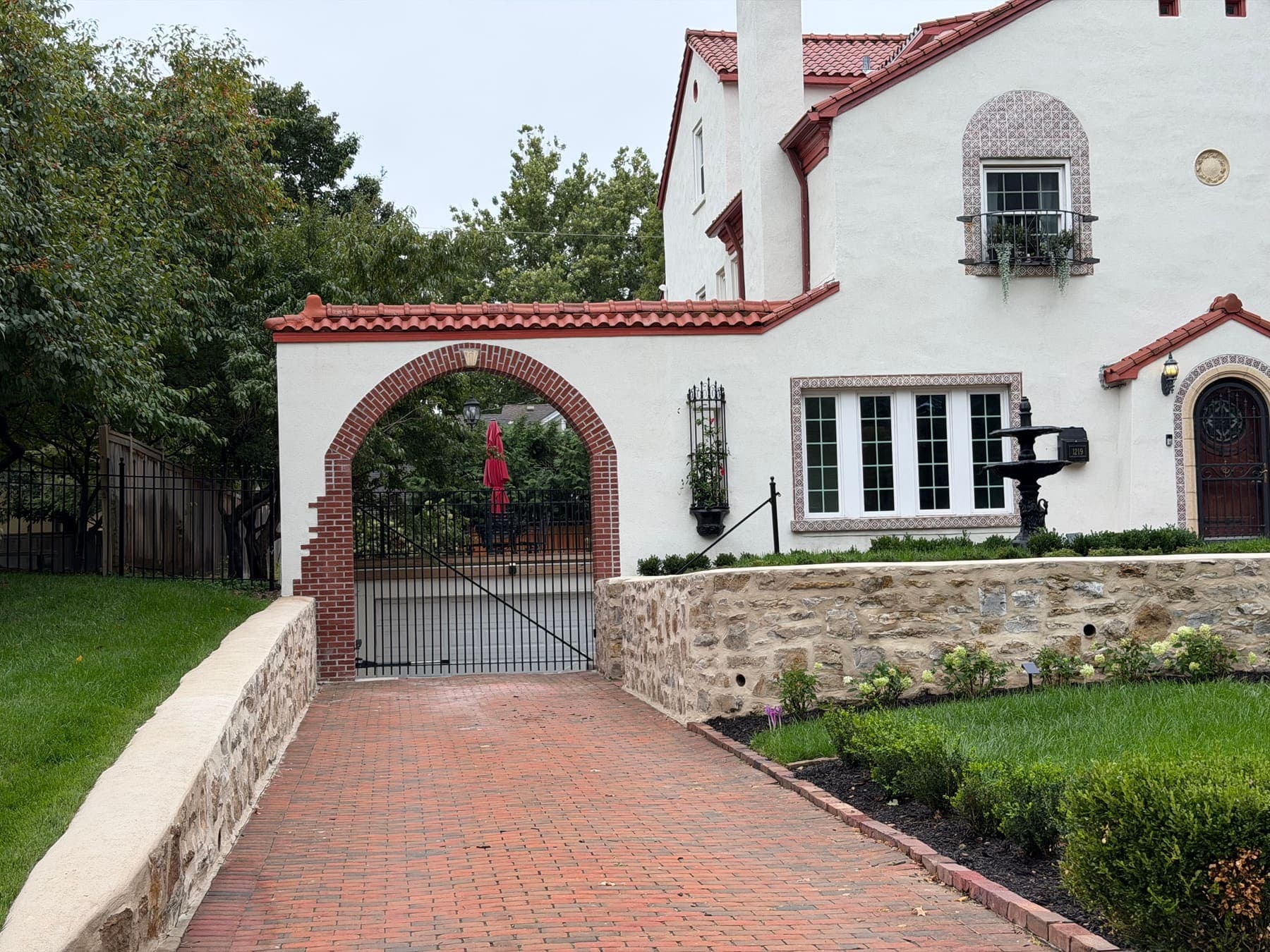 Brick driveway, brick-lined arch, and stone retaining walls